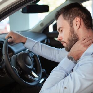 Young man rubbing his aching neck, looking tired from driving. Male driver having neck pain, sitting in his car